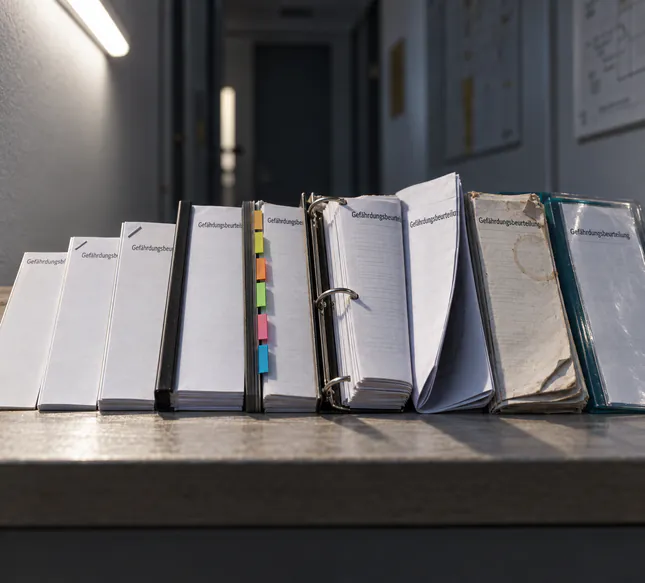 Acht unterschiedliche Gefährdungsbeurteilungen nebeneinander, vom Deckblatt bis zu sechs Seiten