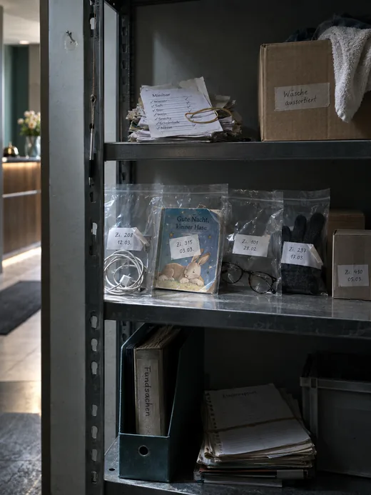Fundsachenregal im Nebenraum hinter dem Empfang, beschriftete Klarsichtbeutel mit Zimmernummer und Datum