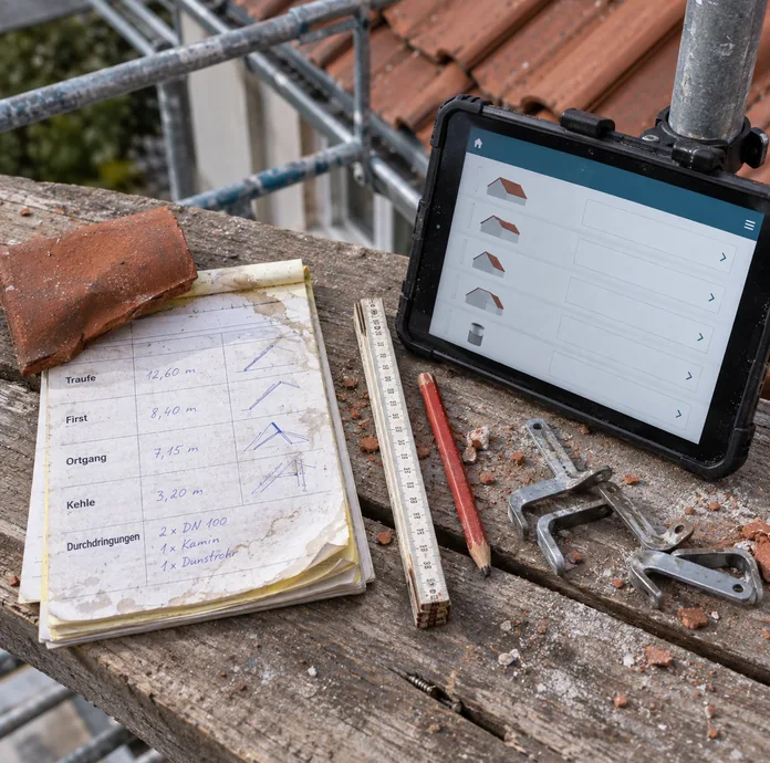 Auf den Bohlen eines Dachgerüsts liegt ein handschriftlich ausgefüllter Aufmaßblock mit Traufe, First, Ortgang, Kehle und Durchdringungen, beschwert mit einem Ziegel, daneben ein Tablet an der Gerüststange mit derselben Gliederung