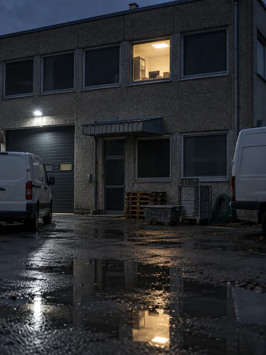 Gewerbehof am Abend, in einem Büro brennt noch Licht