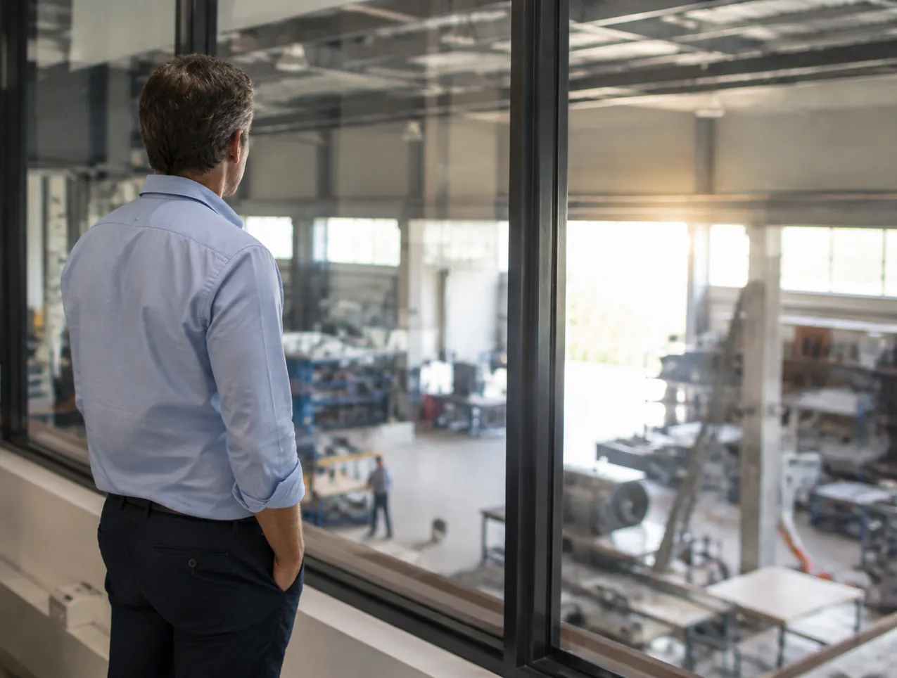 Unternehmer blickt vom Büro aus in die Werkstatt