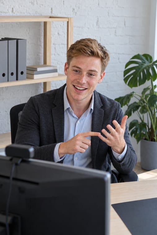 Formilo-Berater im Sakko erklärt im Online-Meeting vor seinem Monitor mit Webcam, wie der individuelle Arbeitsbericht für Handwerker entsteht