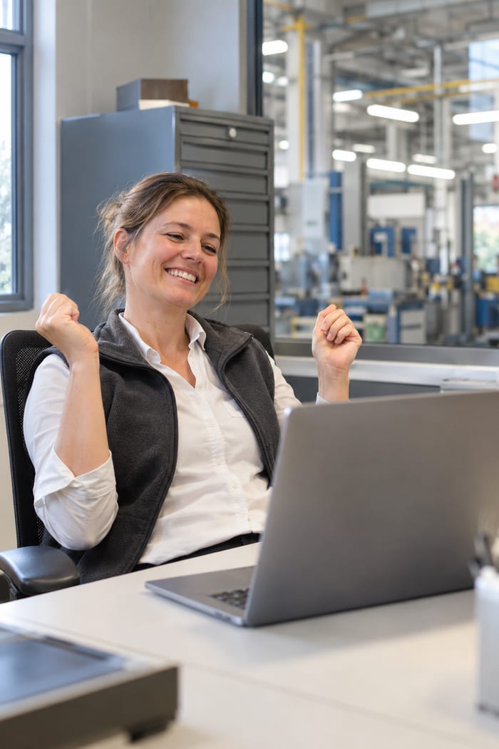 Qualitätsbeauftragte freut sich neben der Fertigungshalle über ihren digitalen Kalibrierplan