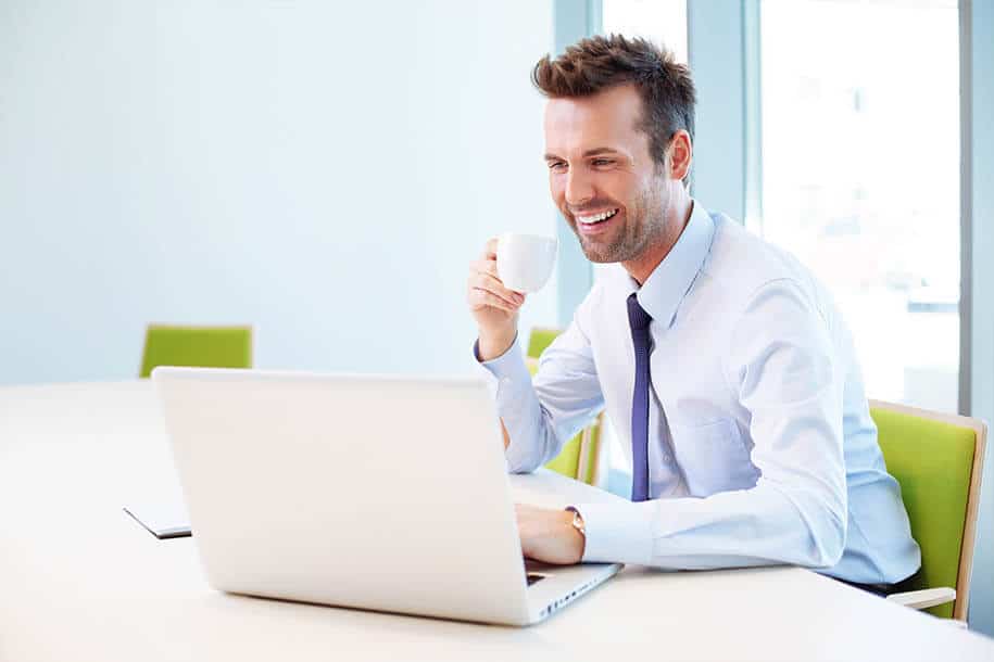 Mann vor seinem Laptop hält lächelnd Kaffee in der rechten Hand. - PDF Felder zum Ausfüllen erstellen - Formilo GmbH