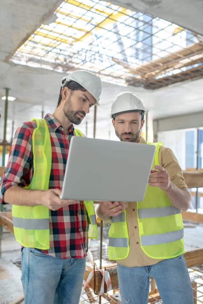 Bauerbeiter schauen auf Laptop auf einem Bauobjekt