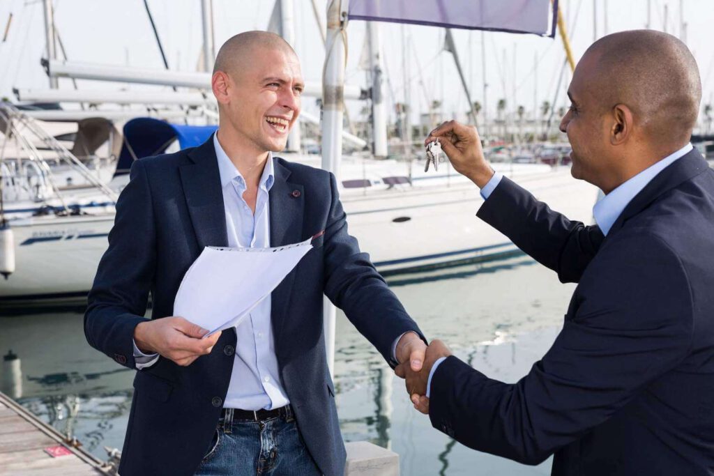 Mann übergibt Schlüssel für ein Boot mit Kaufvertrag