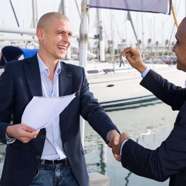 Mann übergibt Schlüssel für ein Boot mit Kaufvertrag