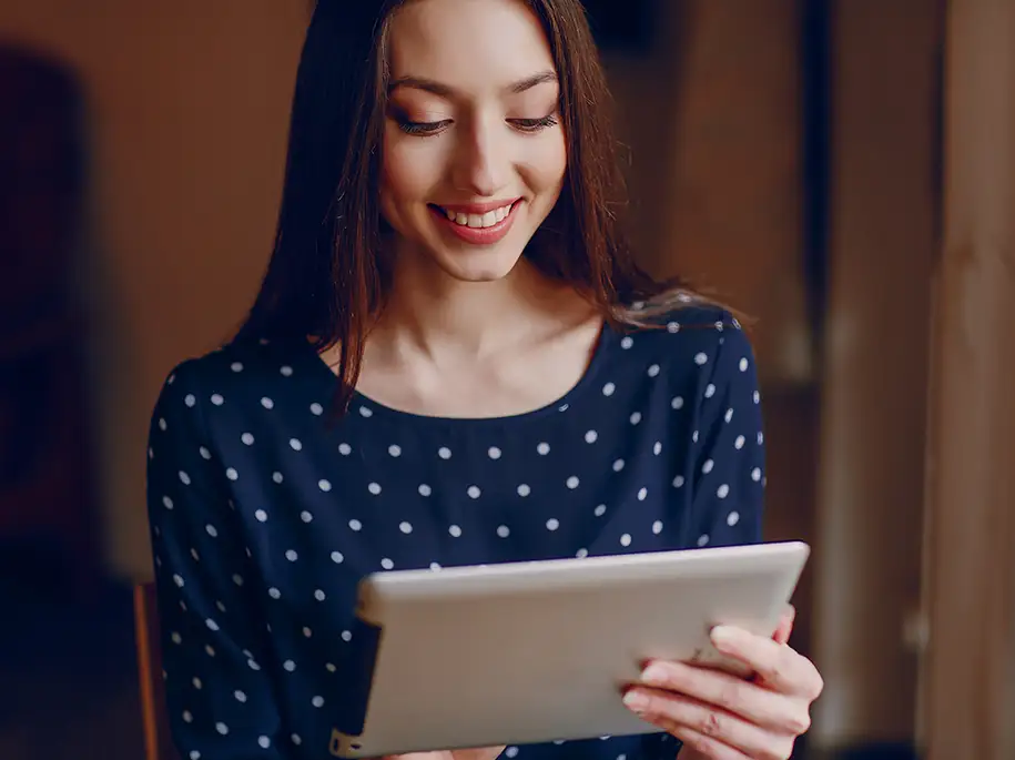 Frau lächelt und schaut auf Tablet