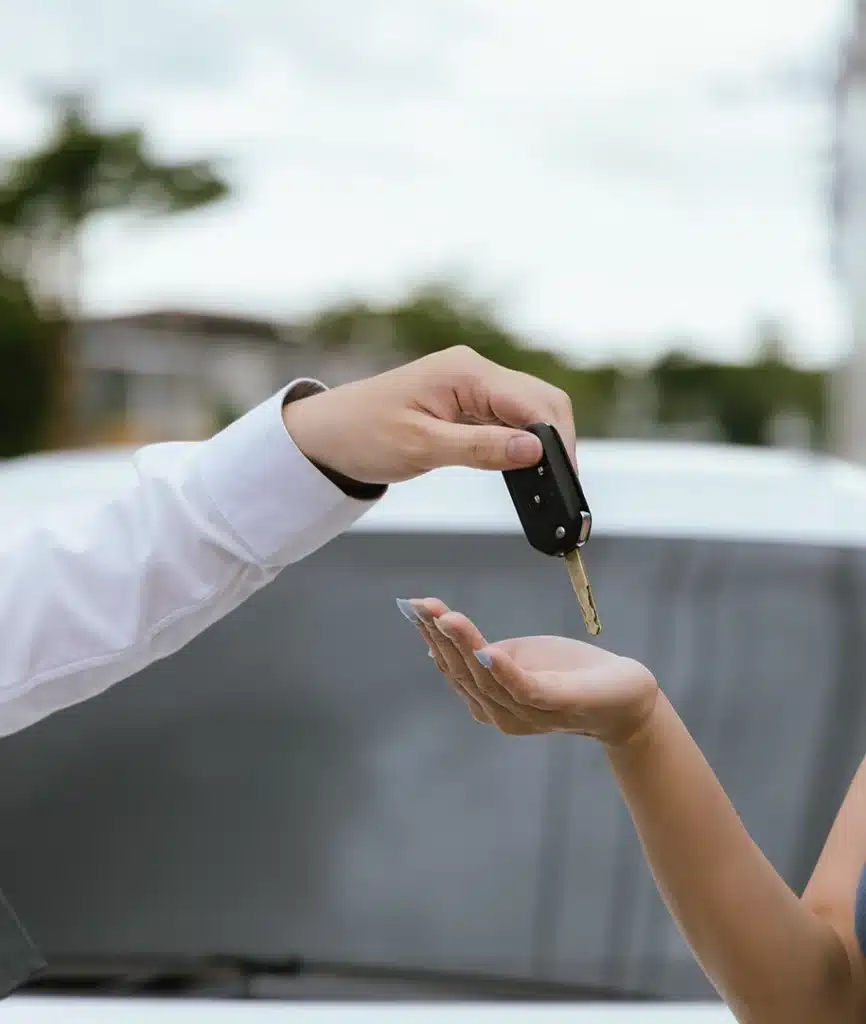 Eine männliche Person übergibt einer weiblichen Personen einen Autoschlüssel