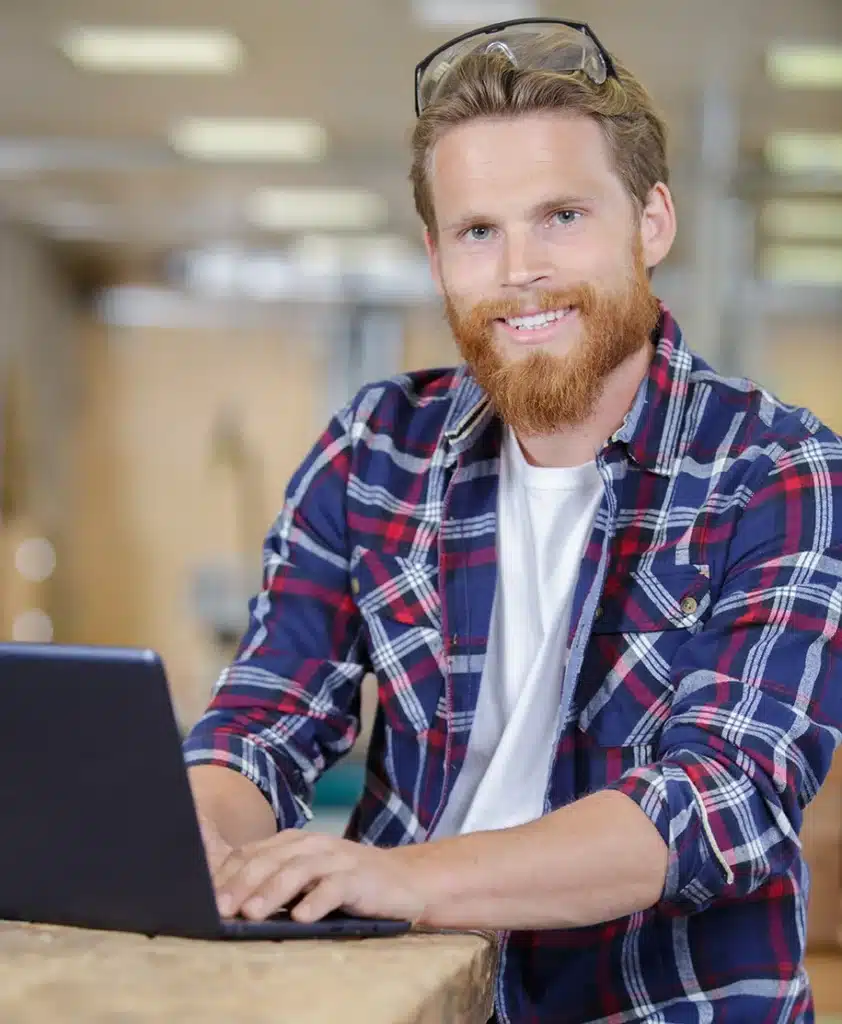 Handwerker arbeitet in der Werkstatt an einem Laptop
