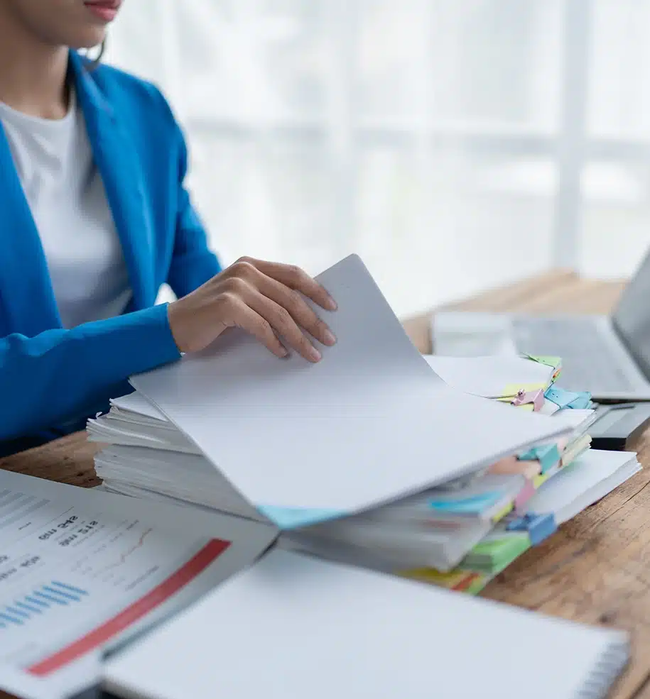 Frau sitzt im Büro am Schreibtisch und führt bürokratische Arbeiten durch