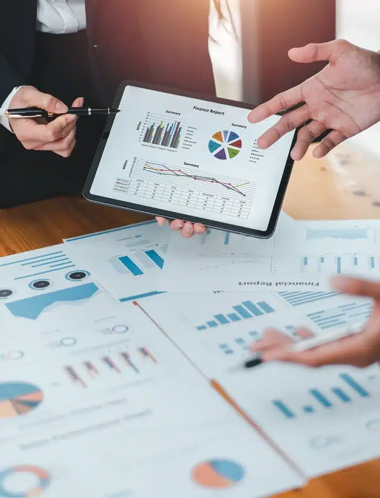 Ein Geschäftsteam bespricht Finanzberichte mit Diagrammen und Grafiken auf einem Tablet und Papierdokumenten