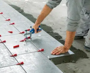 Keramikfliesen. Fliesenleger bringt keramische Wandfliesen mit einem Lash-Fliesennivelliersystem über dem Kleber an