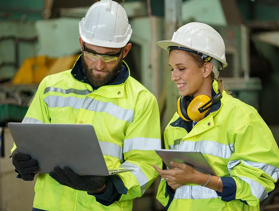 Industriemanager diskitieren auf einer Baustelle anhand einem Laptop