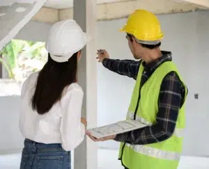 Bauingenieurin mit persönlicher Schutzausrüstung überprüft und berät sich mit dem Vorarbeiter auf der Baustelle