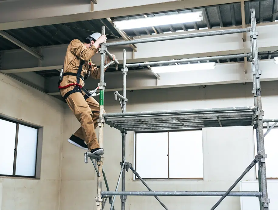 Bauarbeiter besteigt in einer Baustelle ein Gerüst