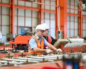 Zwei Mechaniker warten Walzmaschinen in einer Blechfabrik