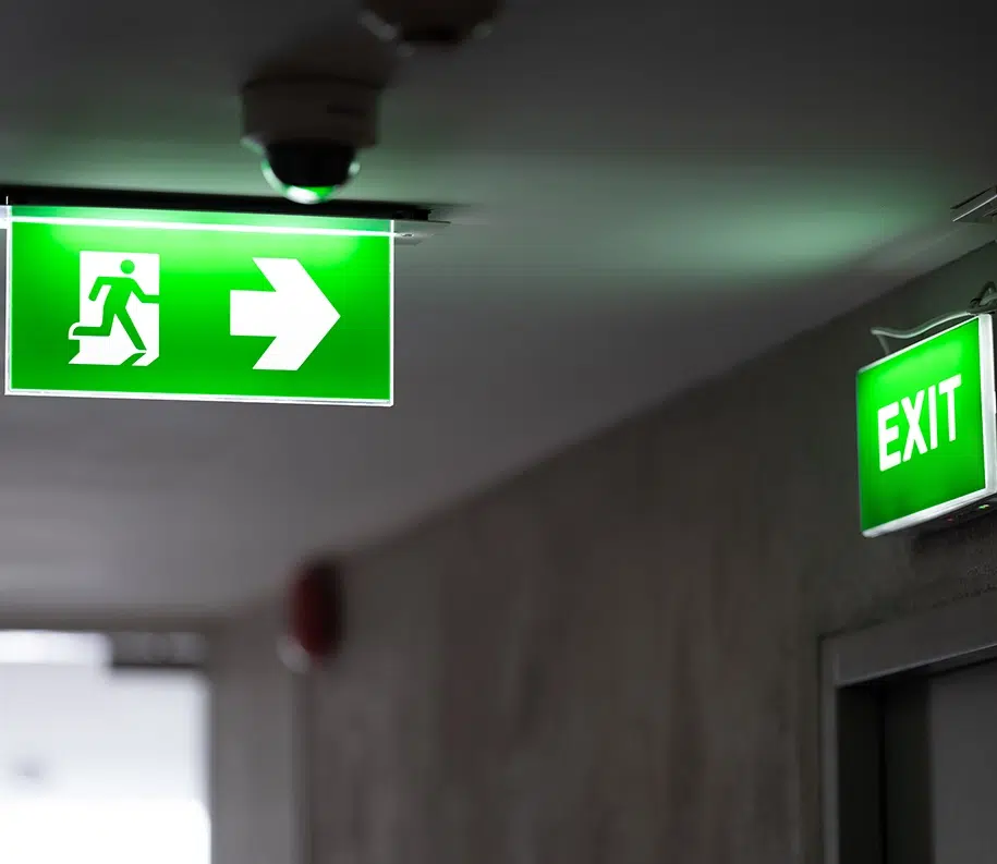 An der Decke ist ein grünes Notausgangsschild angebracht und an der Ausgangstür befindet sich ein grünes Ausgangsschild.