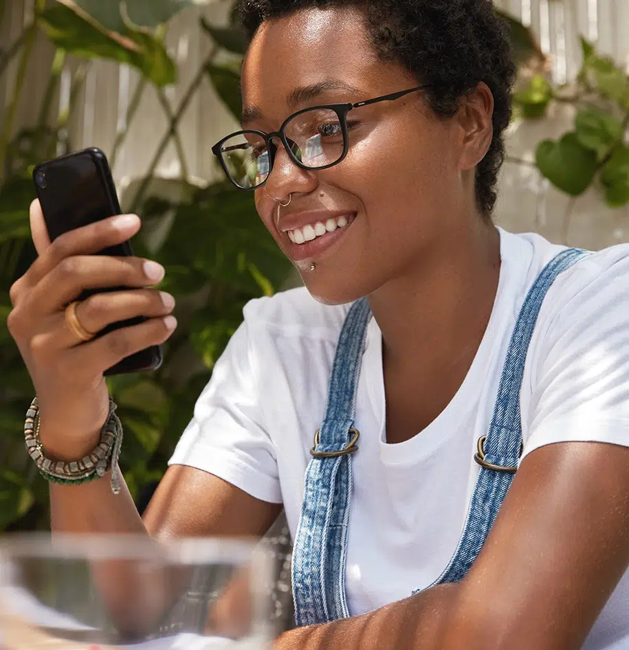 Mädchen mit breitem Lächeln, das Textnachrichten mit einer neuen App auf dem Smartphone sendet