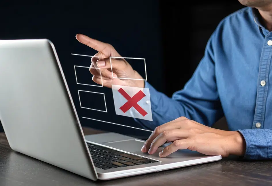 Eine Person zeigt auf den Bildschirm eines Laptops, auf dem eine abgelehnte Auswahl angezeigt wird, was einen fehlgeschlagenen Versuch in der digitalen Dokumentation symbolisiert.