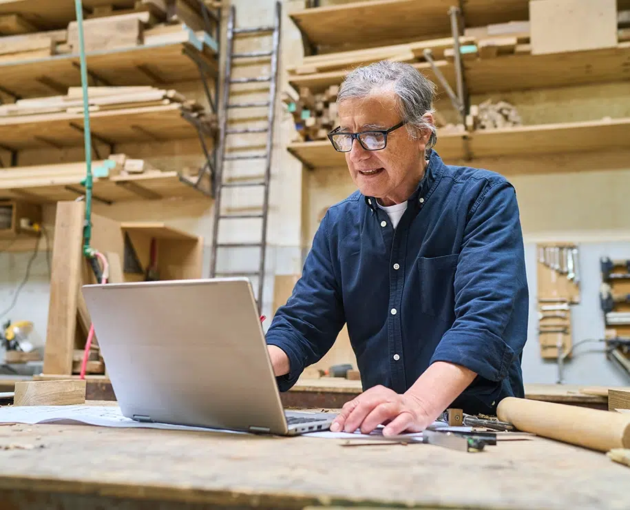 Leitender Handwerker mit Laptop in einer Holzwerkstatt