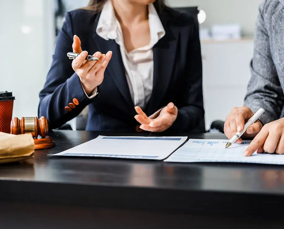 Zwei Anwältinnen in Geschäftsanzügen besprechen am Tisch Finanzdaten
