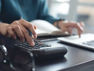 Geschäftsfrau, die mit einem Taschenrechner Unternehmensfinanzen berechnet und Buchhaltungen durchführt