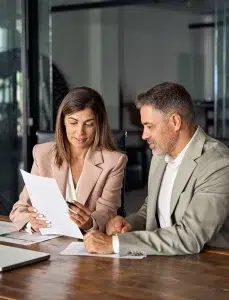 Geschäftsfrau hält juristische Dokumente in der Hand, die einen Kunden bei einer Bürobesprechung beraten.