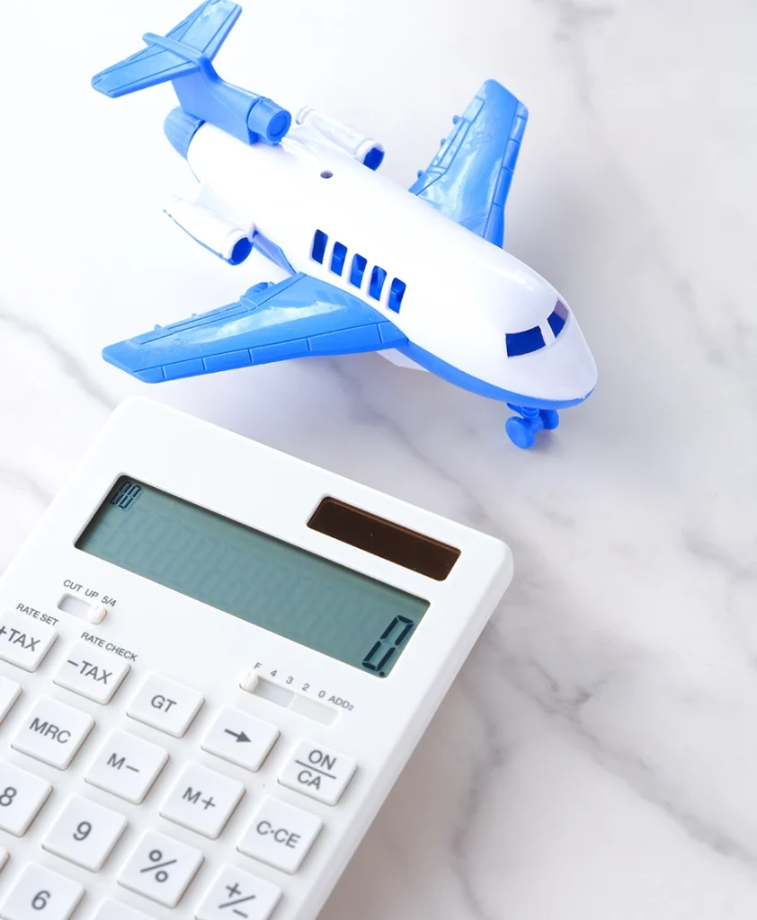 Ein Flugzeug und ein Taschenrechner symbolisieren die Berechnung von Reisekosten