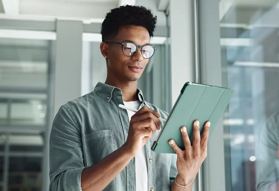 Geschäftsmann steht in einem Büro und hält ein Tablet in der Hand