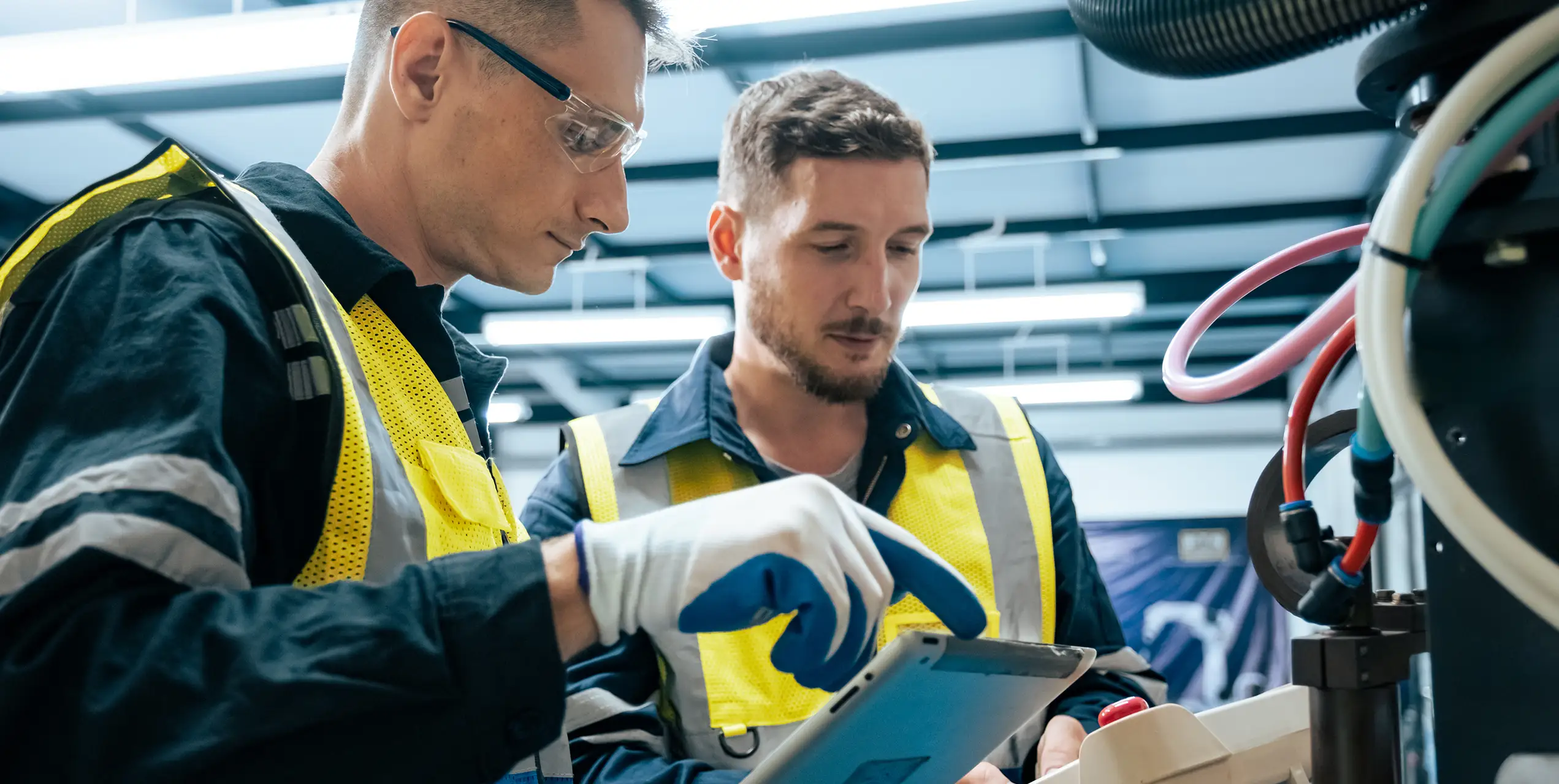 Zwei Techniker gehen eine digitale Wartungsplan-Vorlage in einer Werkstatt durch