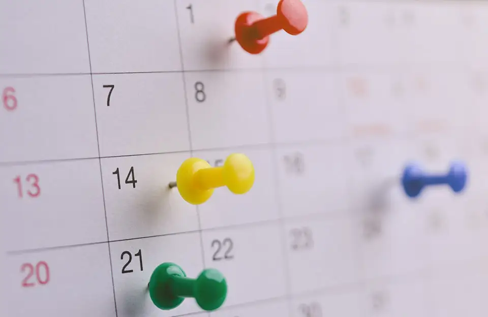 Ein Wandkalender mit bunten Pins