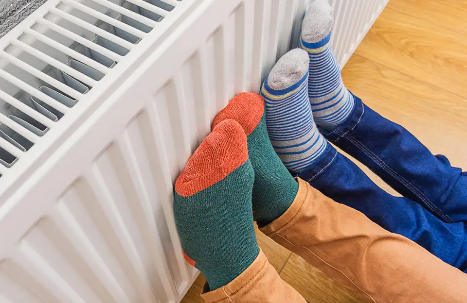 Füße in bunten Socken wärmen sich an einer Heizung