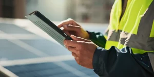 Ein Techniker steht auf einem Dach mit dem Tablet in der Hand
