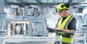 Techniker mit Laptop vor technischen Anlagen