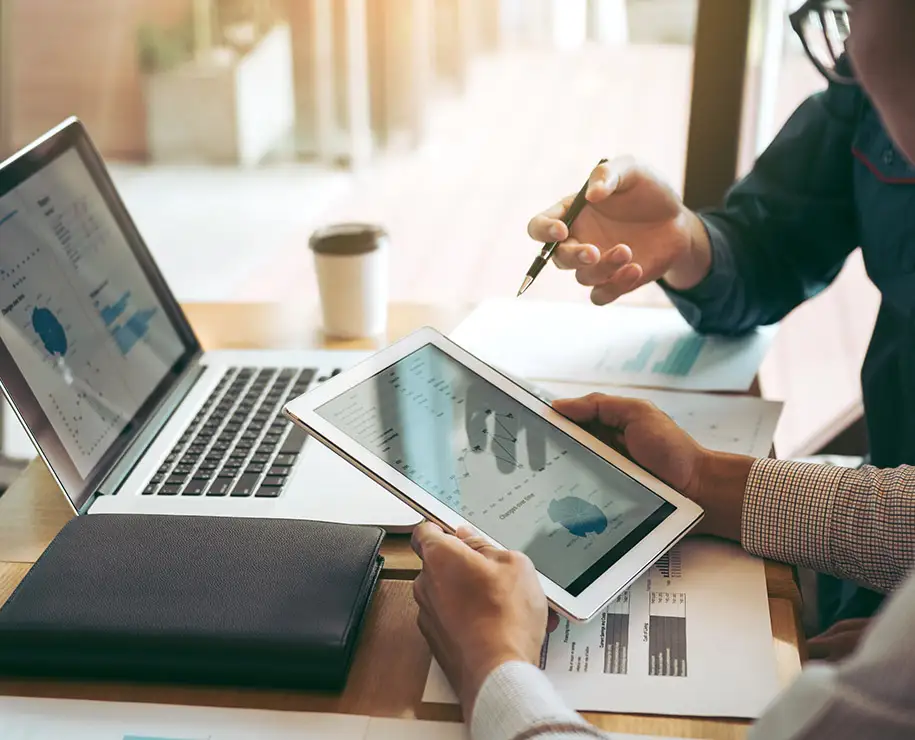 Wartungspläne werden in einem Büro auf Tablet und Laptop verglichen