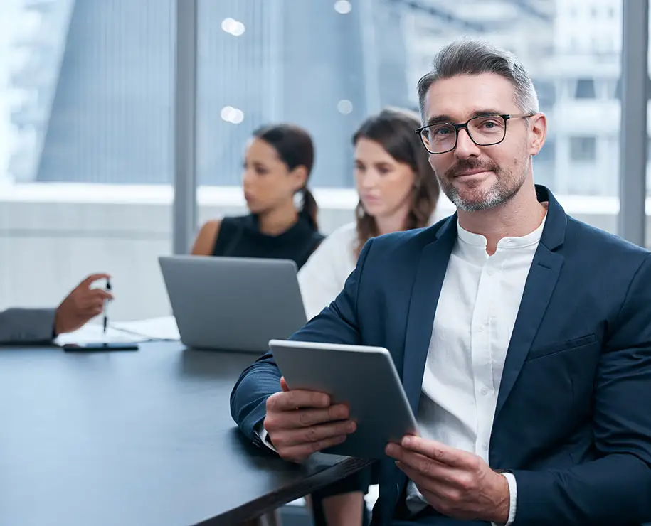 Ein Mann in einem Büro mit einem Tablet lächelt zum Betrachter