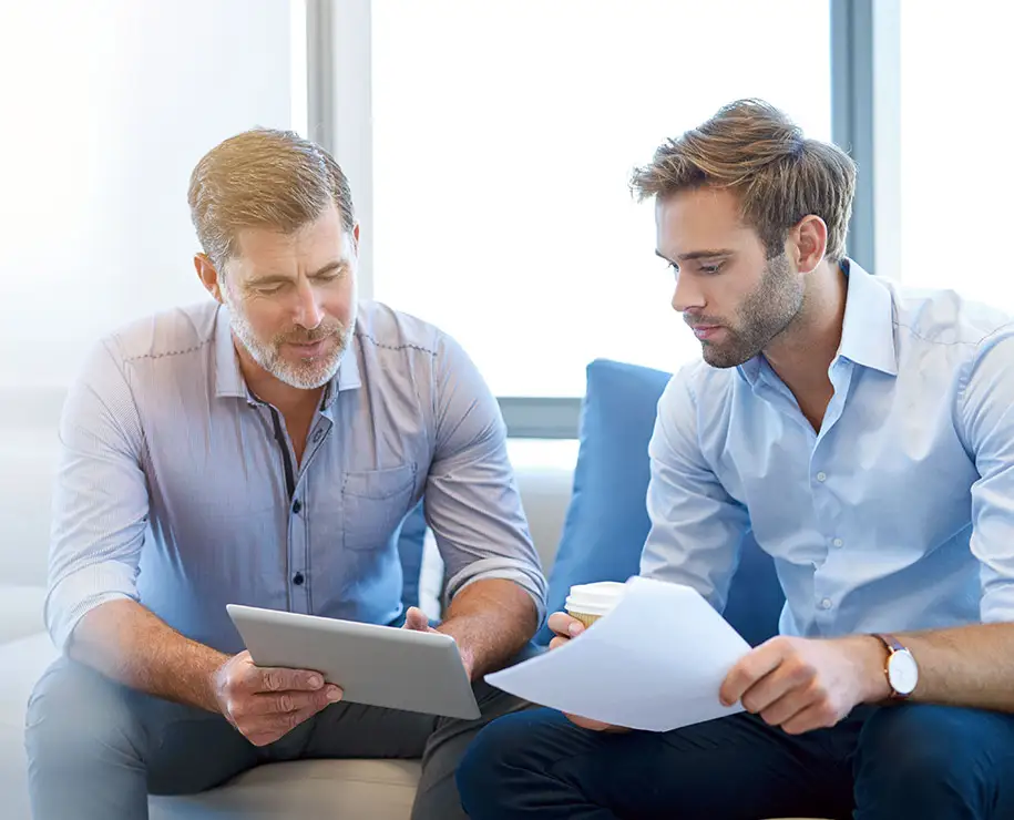 Zwei Geschäftsleute vergleichen Printformularvorlagen mit interaktiven Formularen