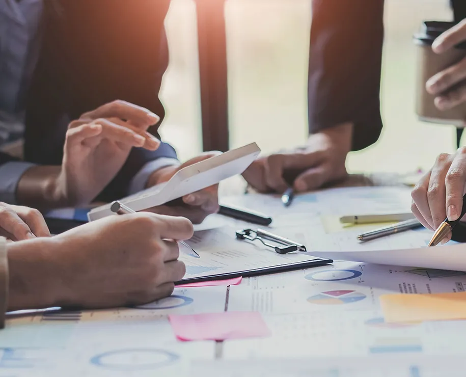 Mitarbeiter sitzen in einem Meeting über Papieren und analysieren diese